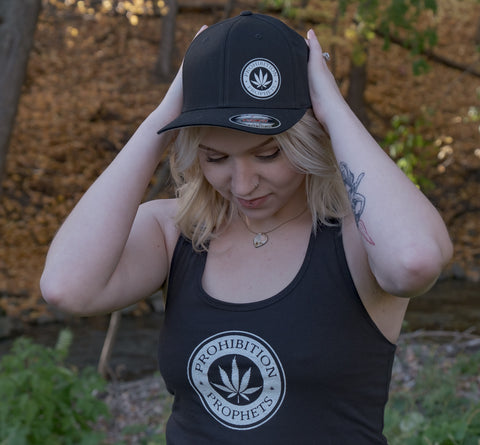 Female wearing black prohibition prophets tank top and black prohibition prophets hat with pot leaf logo design. 